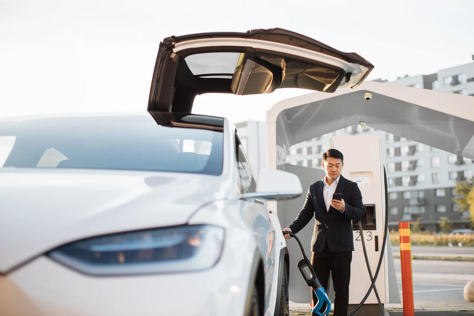 Professional coordinating charging beside a white electric vehicle