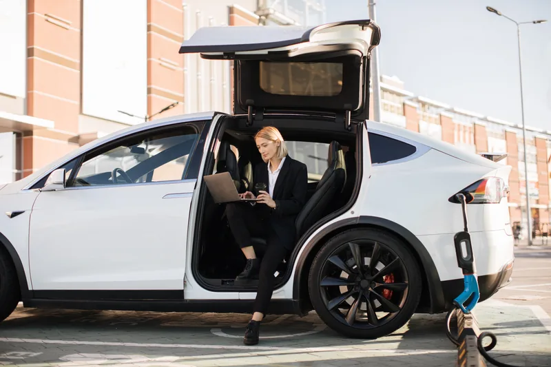 Woman working beside an electric vehicle